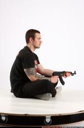Man Adult Athletic White Fighting with submachine gun Sitting poses Sportswear