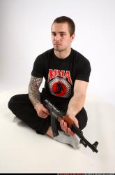 Man Adult Athletic White Fighting with submachine gun Sitting poses Sportswear